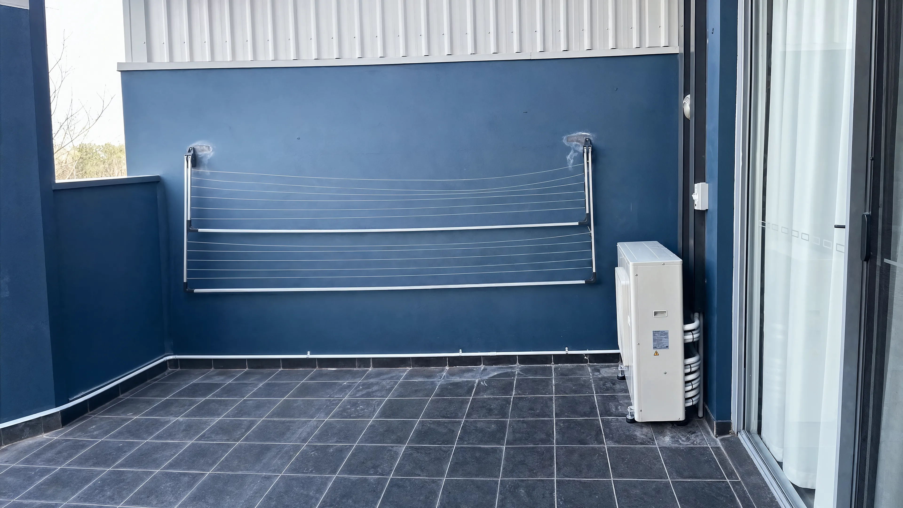 Outdoor air conditioning unit installed on a navy balcony wall by MCM Air Conditioning